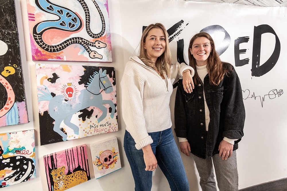 Kured founders standing next to artwork in their store