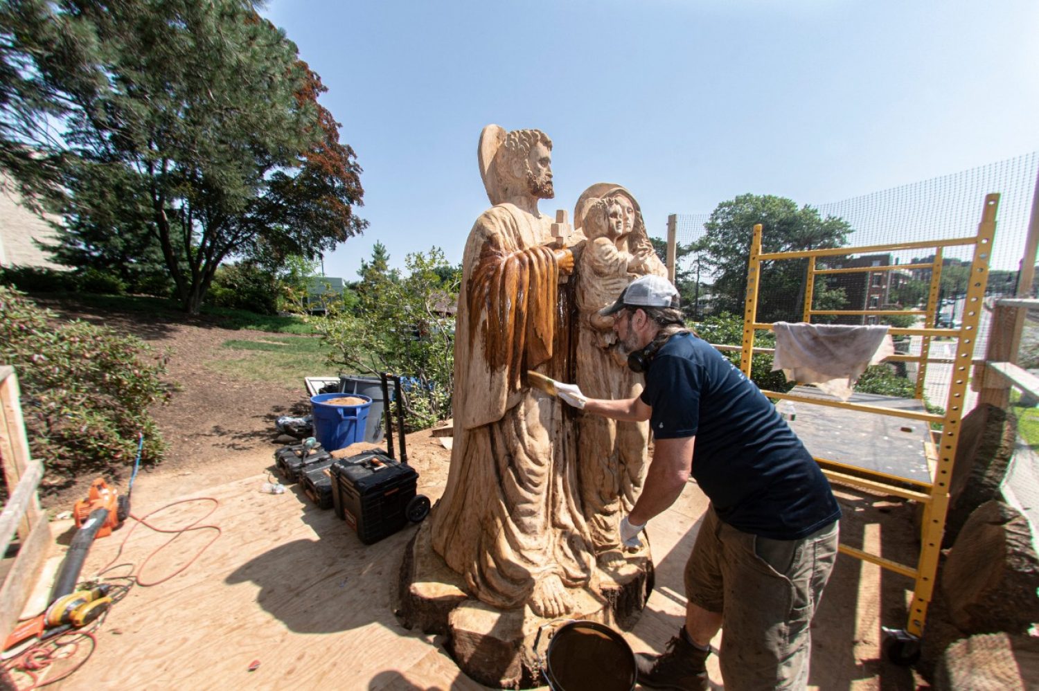 A sculptor chisels a wood statue of the Holy Family