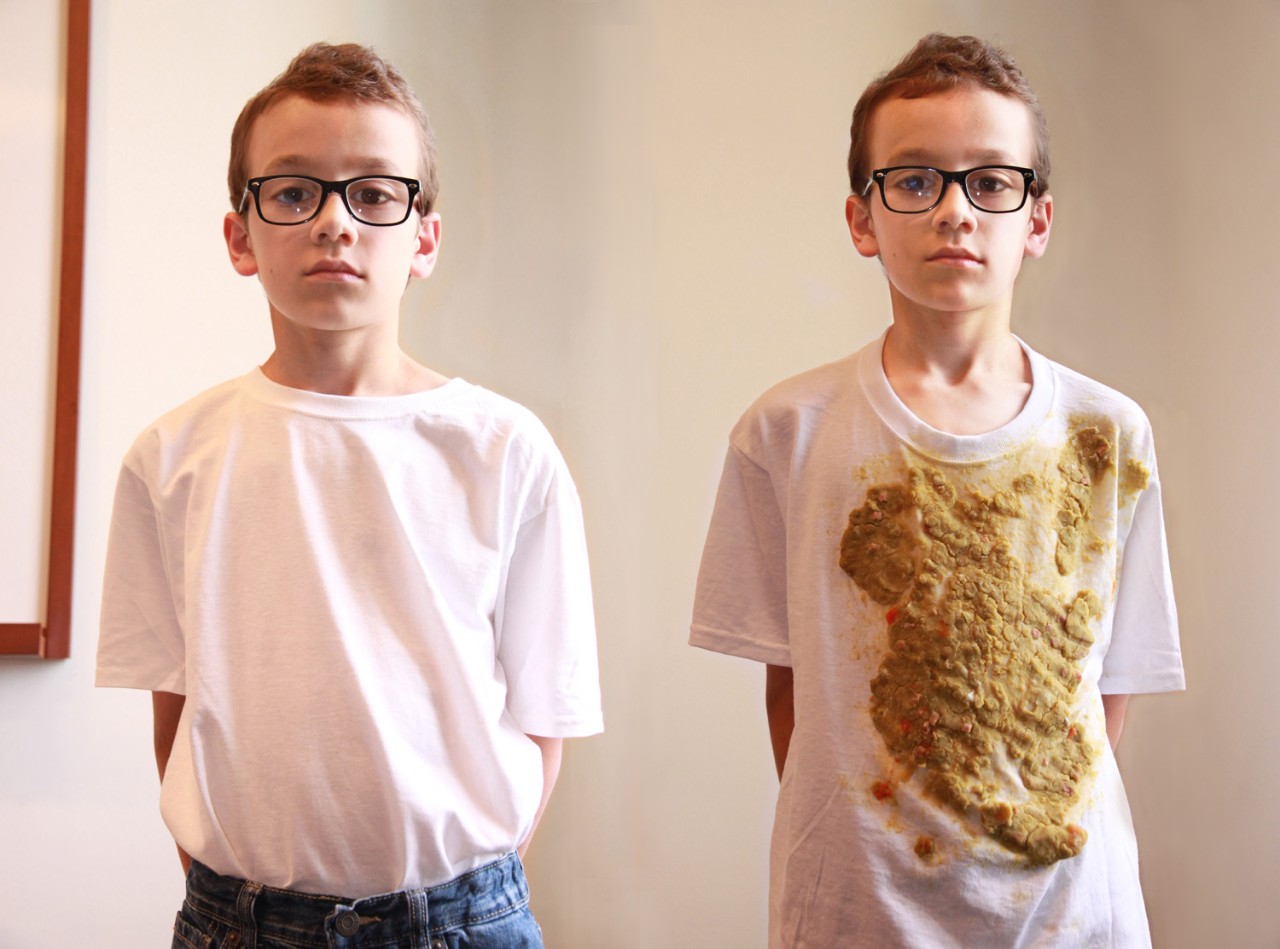 Two identical young boys, one wearing a clean t-shirt, the other wearing a dirty t-shirt