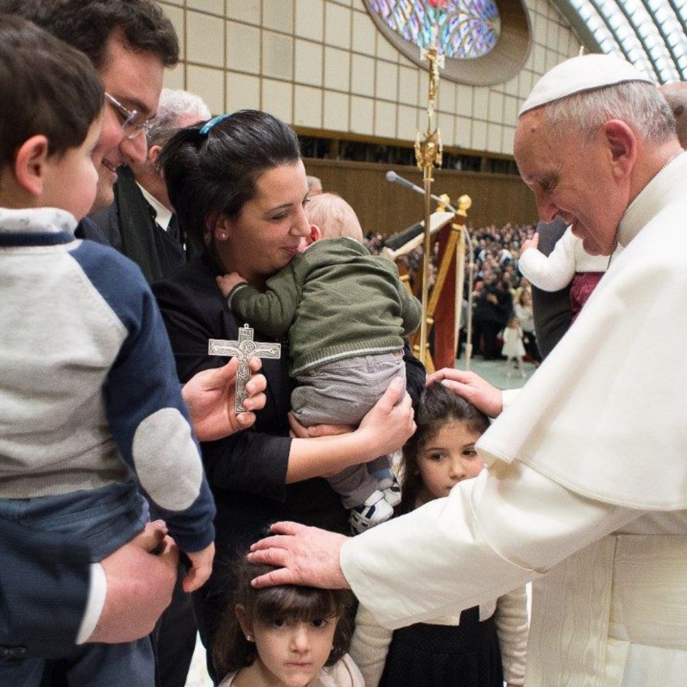 Pope Francis blessing two children with their parents