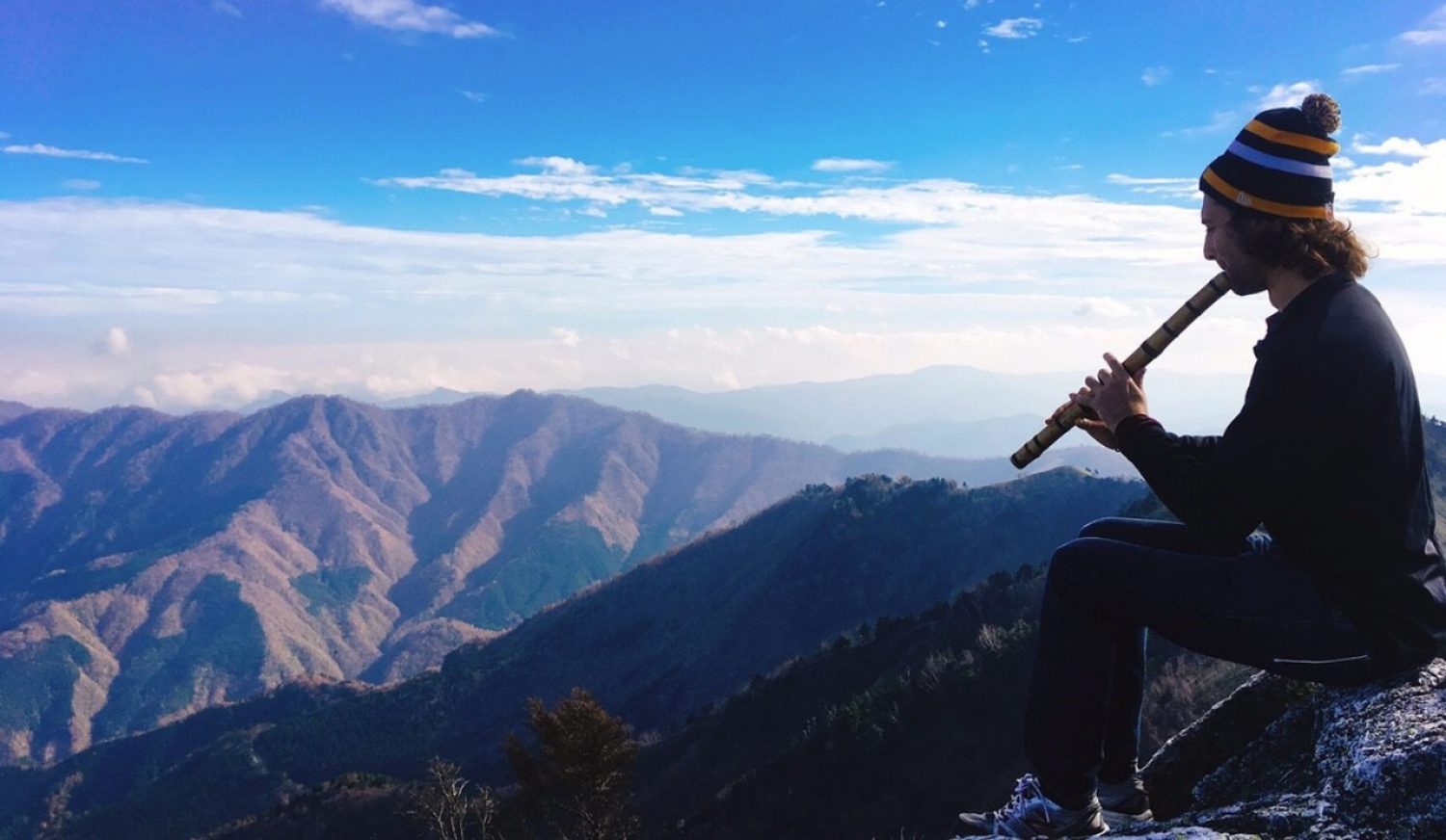 A person playing an instrument on top of a mountain