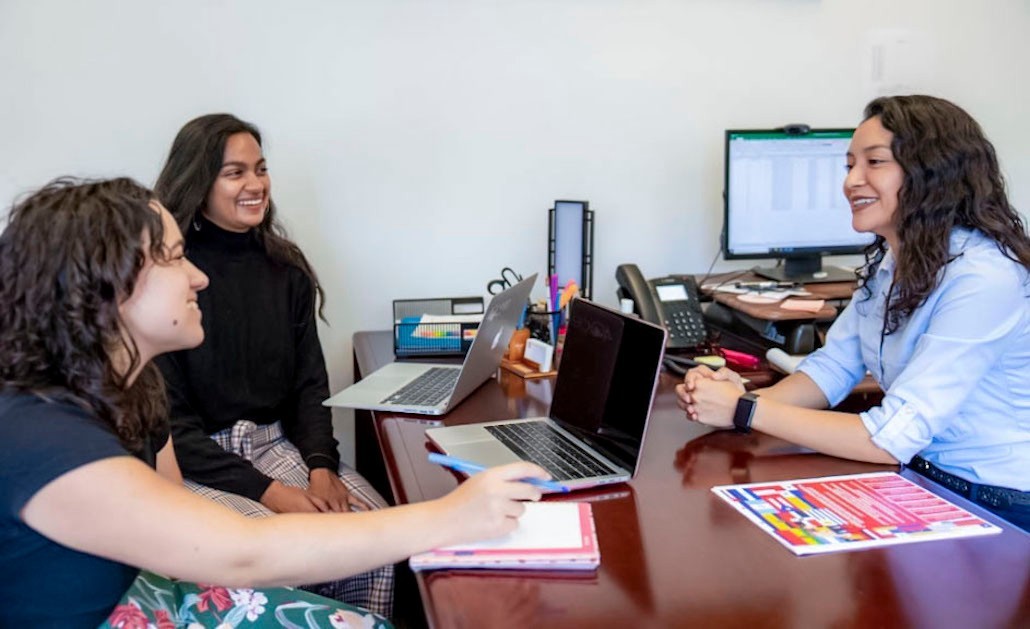 Assistant professor María Piñeros-Leaño talks with two students.