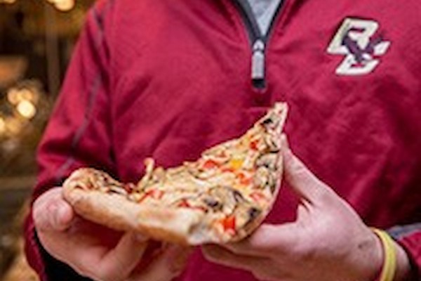 Student holding a pizza slice