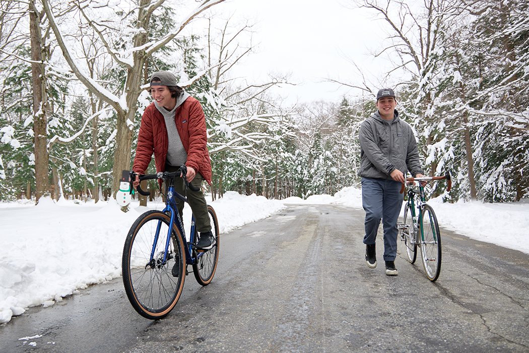 Two young people riding bikes on a snowy road
