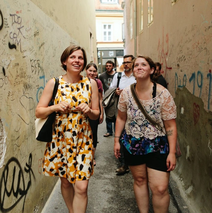 two women walk down alley looking up