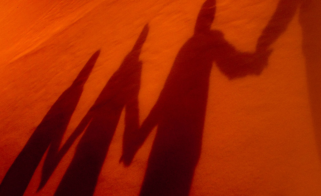 A photo of shadows of four people holding hands