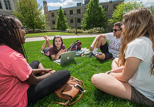 students on a lawn with laptops