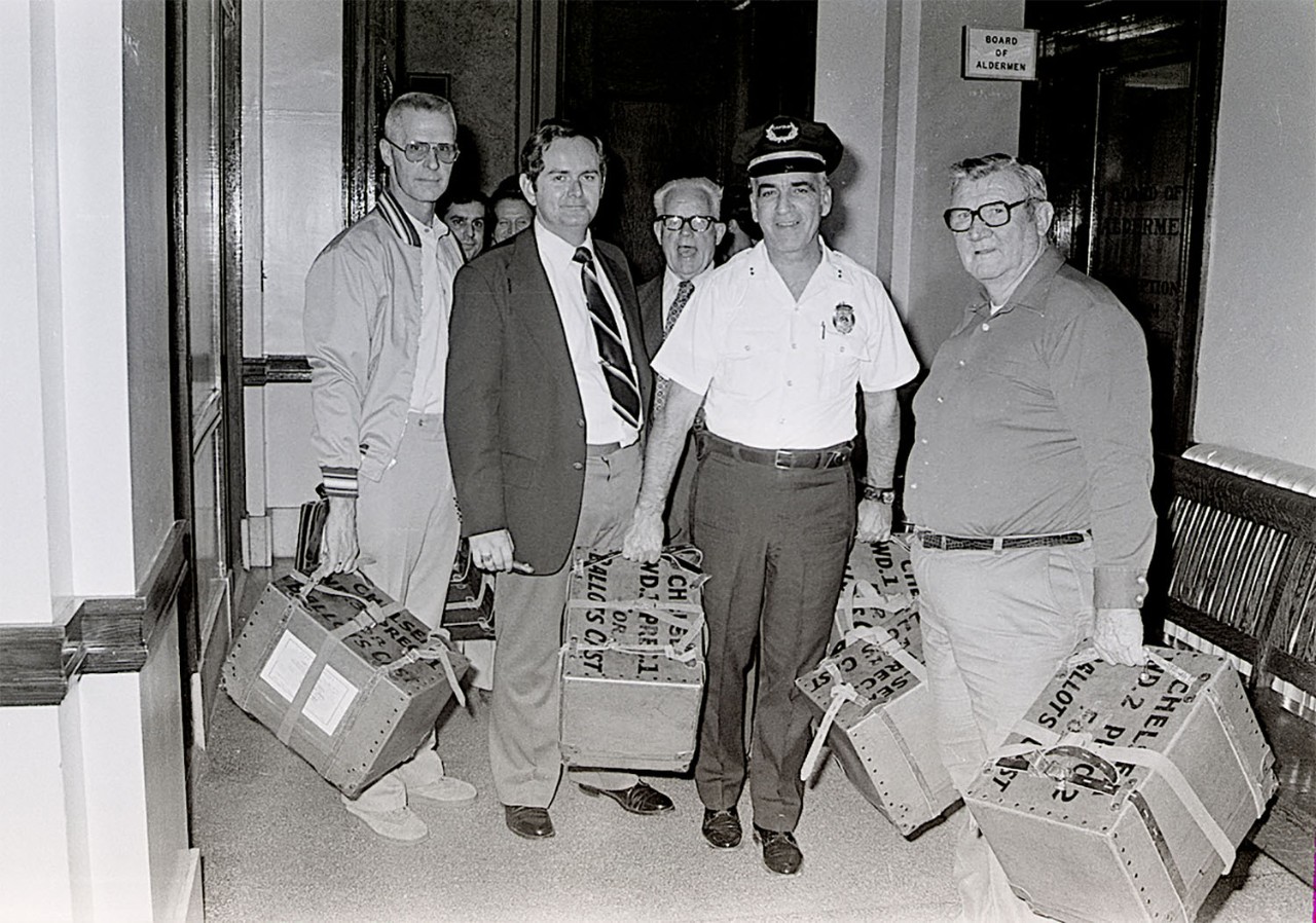 Black and white photo of men holding boxes