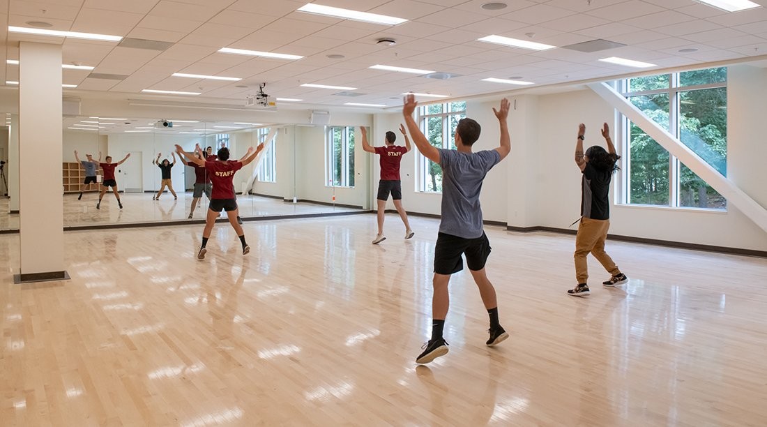 Students doing jumping jacks in a brightly lit room