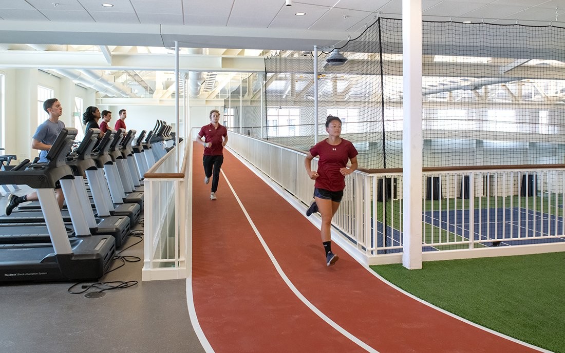 Two students running on an elevated indoor track