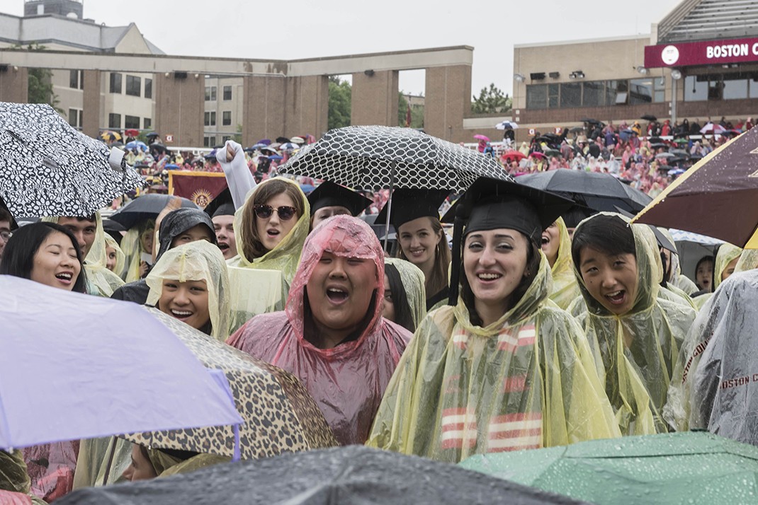 Scene from Alumni Stadium at BC Commencement; umbrellas and students in rain ponchos