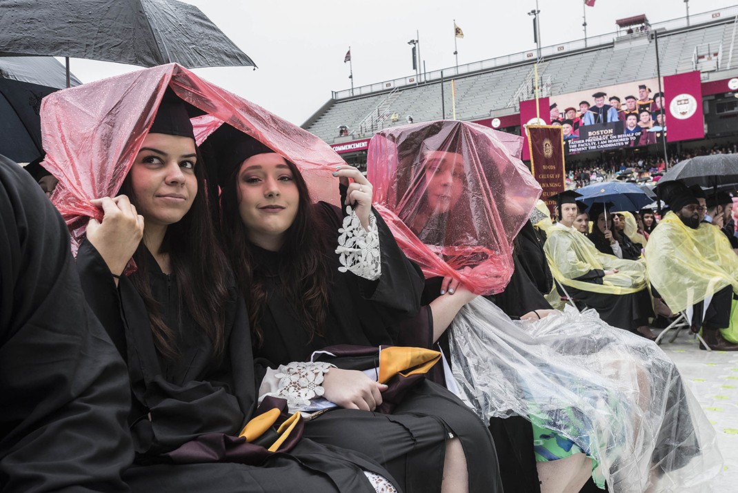 Scene from Alumni Stadium at BC Commencement; umbrellas and students in rain ponchos