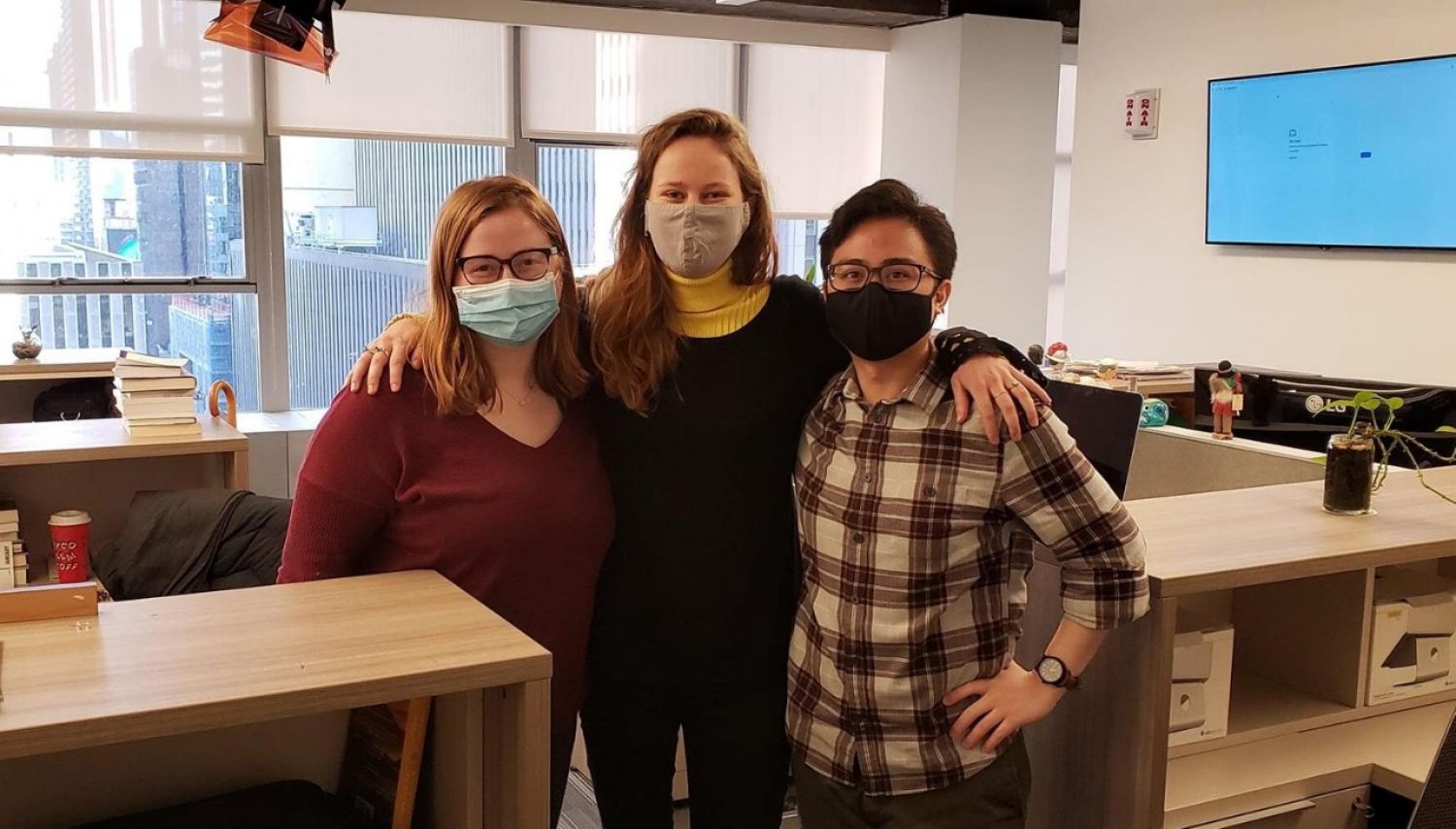 Three people wearing masks standing in an office