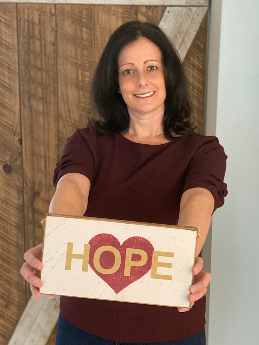 Melanie O'Neil holding a maroon and gold heart sign