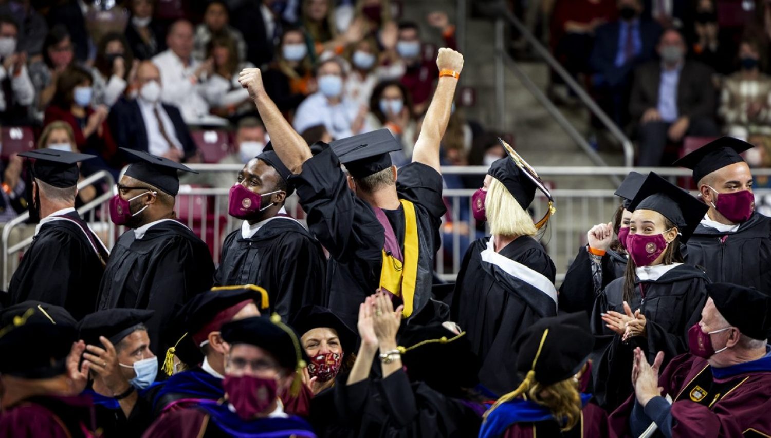 A student raising their hands in the air during a Commencement ceremony