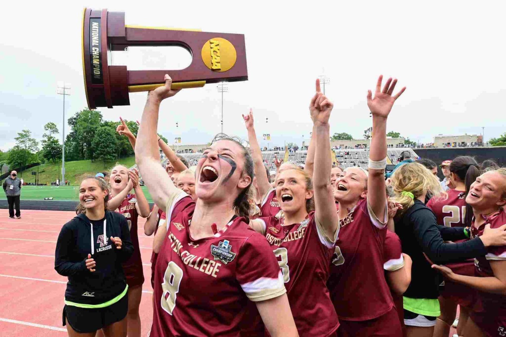 A student athlete holding a trophy above her head