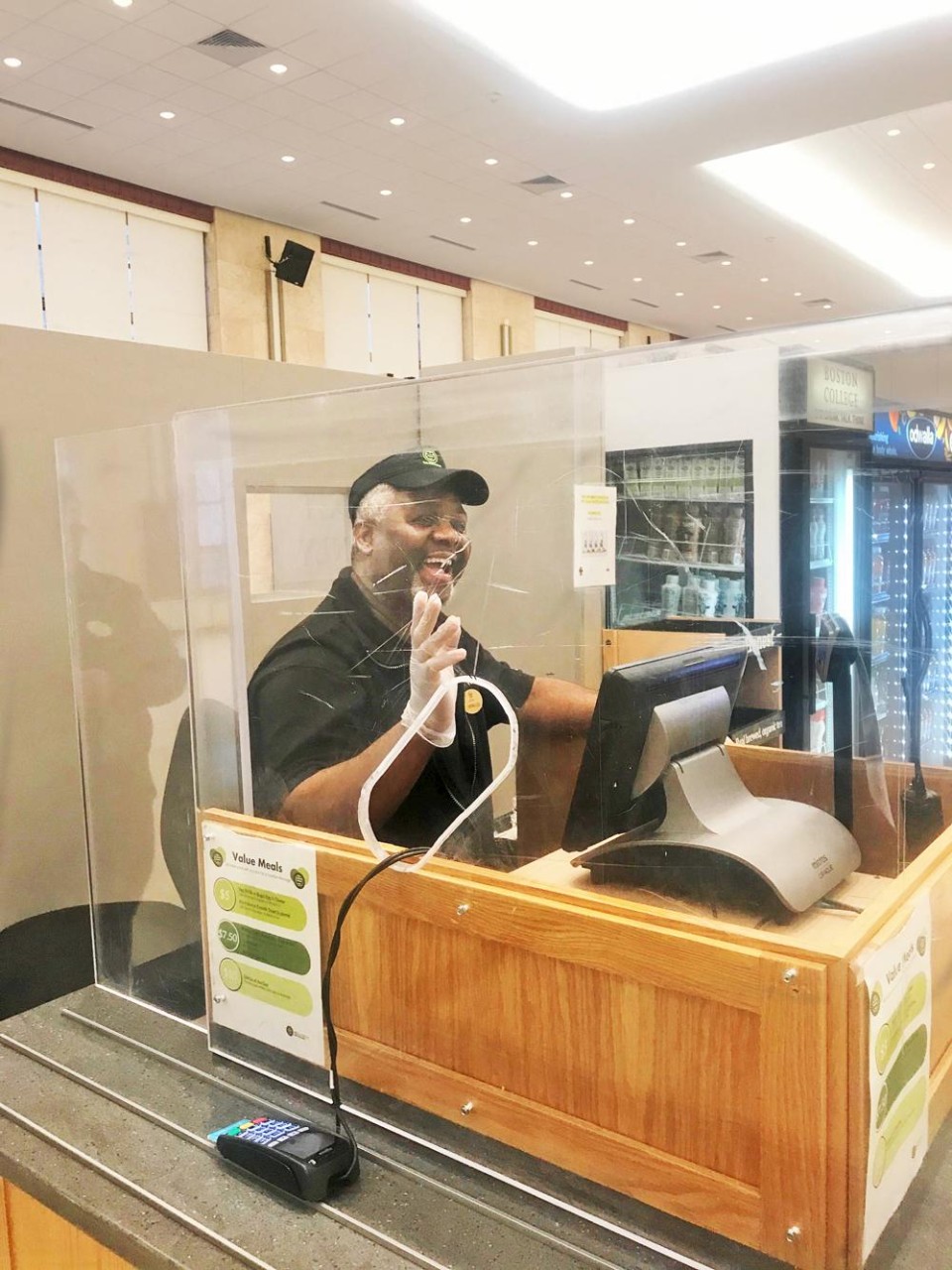 A cashier sitting behind plexiglass at a dining hall