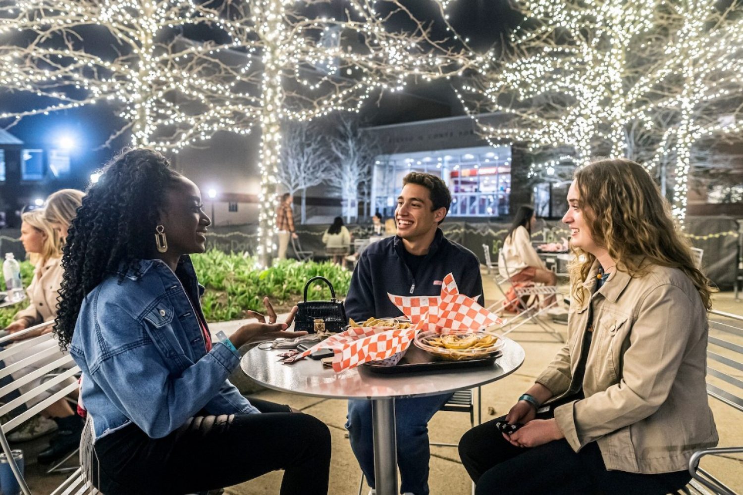 Three students eating outside at night