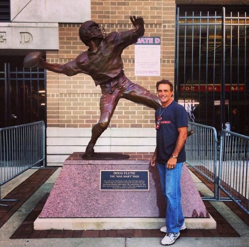 Doug Flutie in front of the campus statue in his honor.