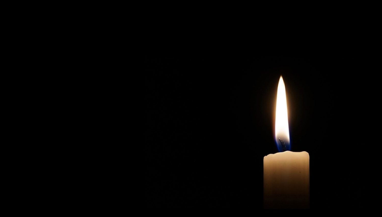 A lit candle against a black backdrop