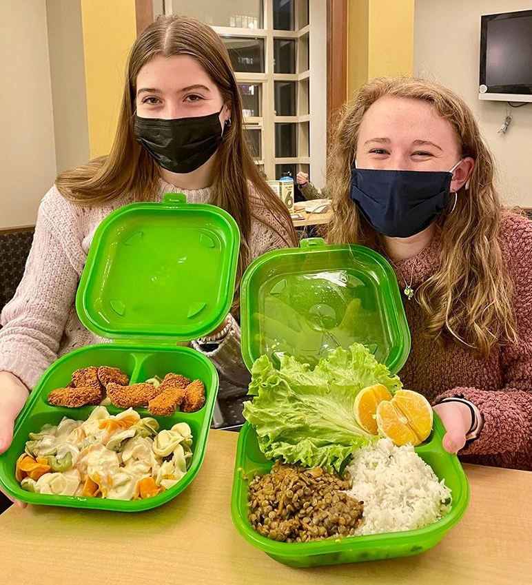 two people holding green plastic food containers