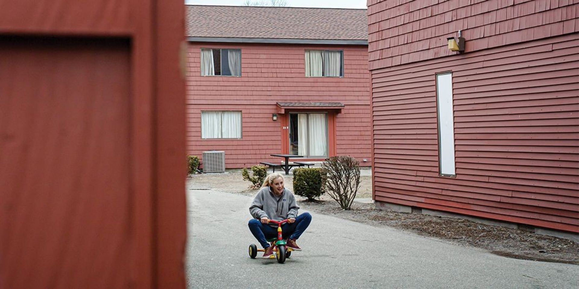 A student riding a tricycle outside the mods