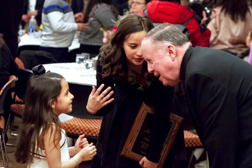 University President William P. Leahy, S.J., chats with Tiru with her little cousin Isabela Sofia Isidro at the awards banquet.