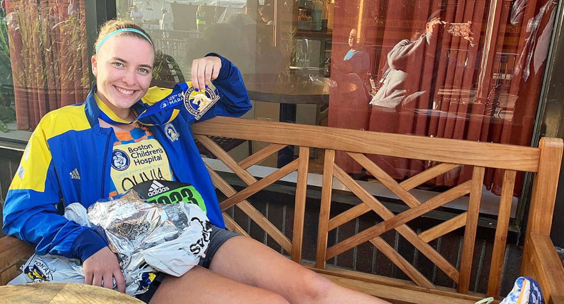 Olivia Colombo sitting on a bench holding a medal