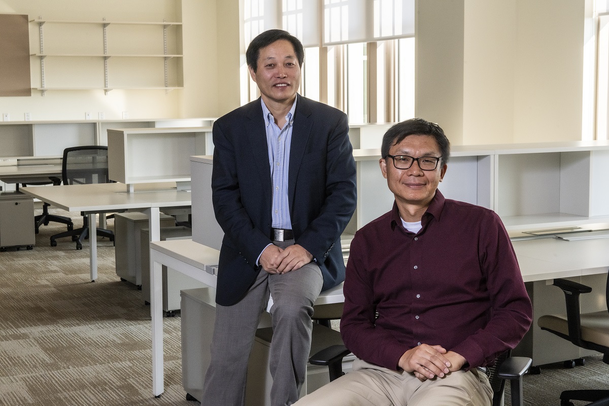 Hanqin Tian, Institute Professor of Global Sustainability, Earth & Environmental Sciences (standing) and Yi Ming, Institute Professor of Global Sustainability, Earth & Environmental Sciences (seated) in 245 Beacon St. photographed for an article in the 9/15 issue of Chronicle.
