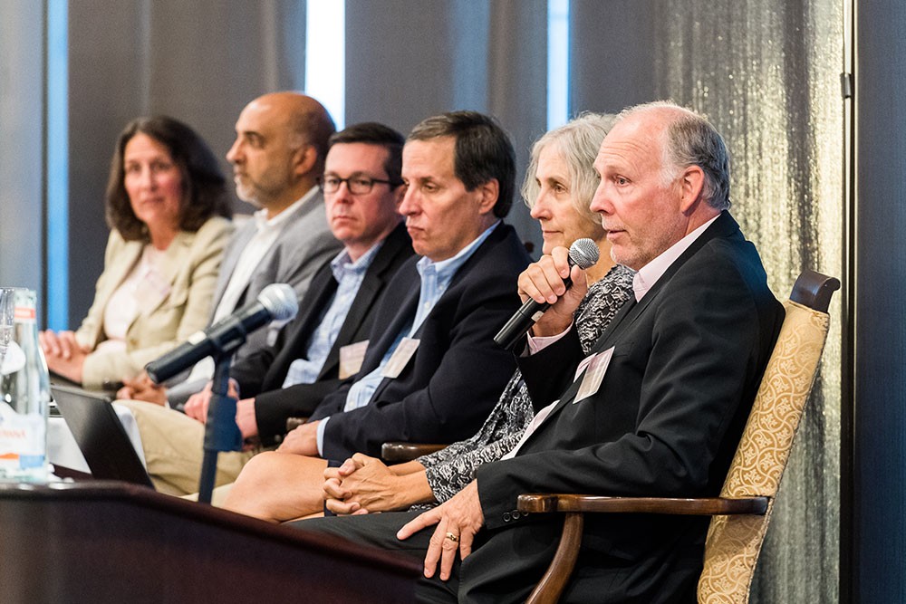 Six panelists seated on stage