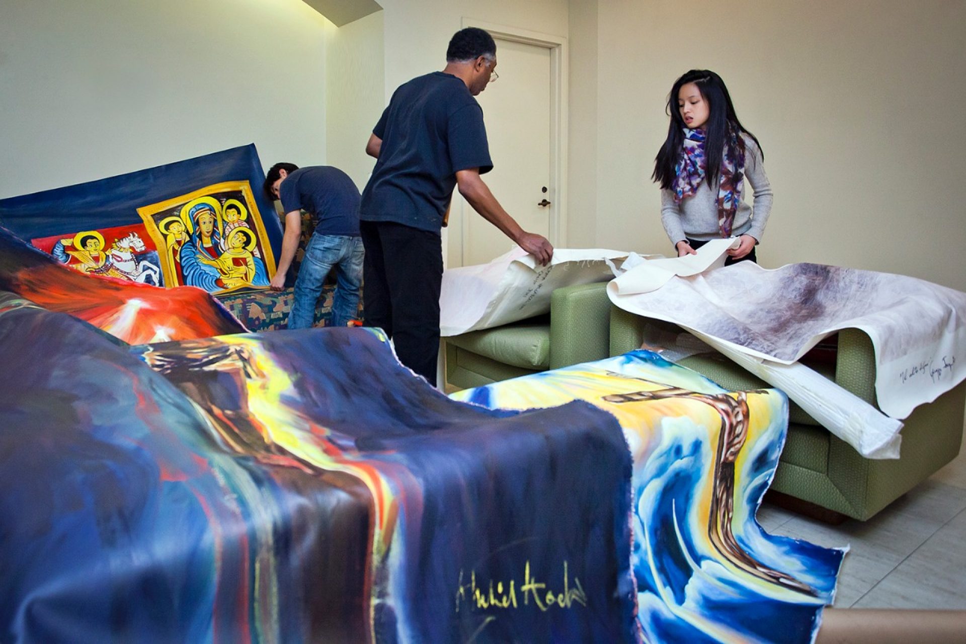 Adjunct Professor of Fine Arts Khalid Kodi with Art Club students, installing artwork in the Bapst Library gallery space. The artwork is related to a  project that relates to the principles and commitment to peaceful co-existence and social justice. 