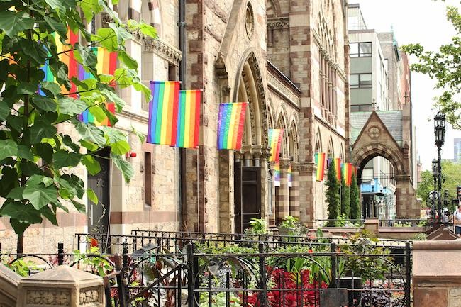 Exterior of church with mulitple rainbow flags hanging
