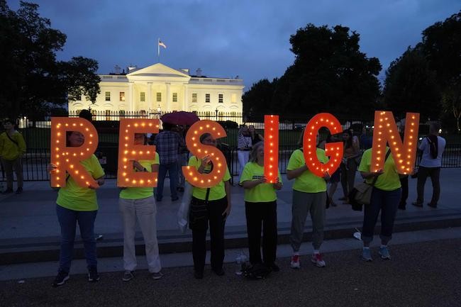 People holding up Resign outside White House
