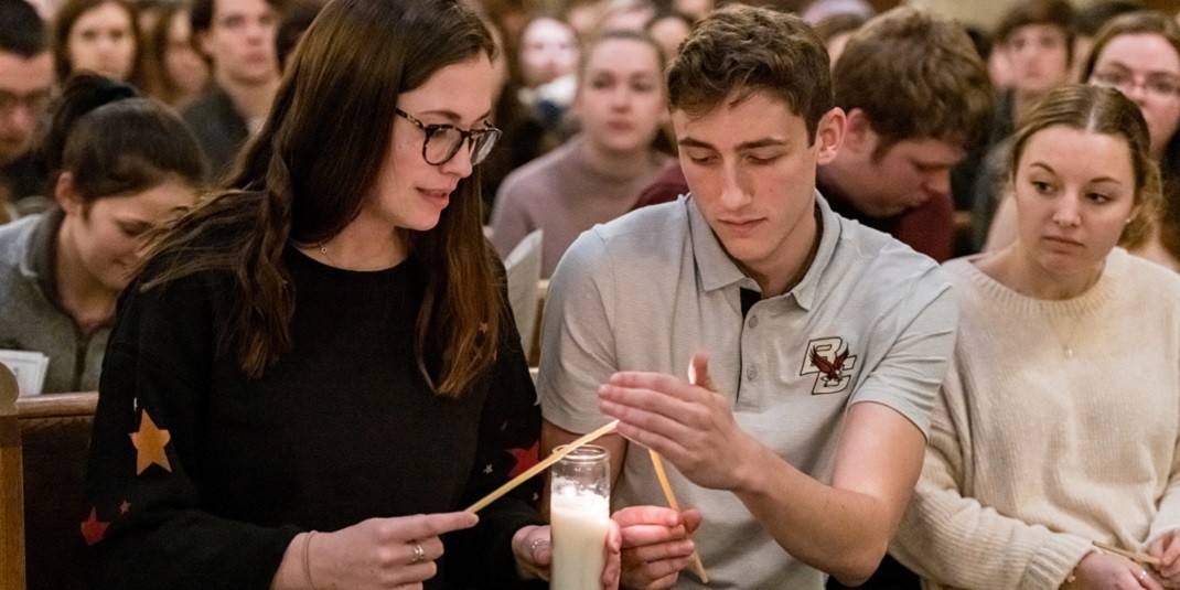 Students lighting a candle together during Mass