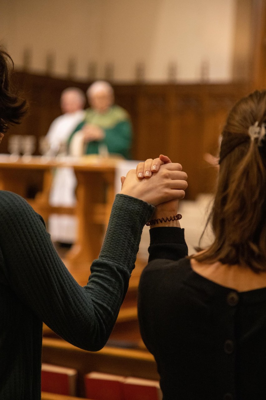 Students holding hands to pray during Mass
