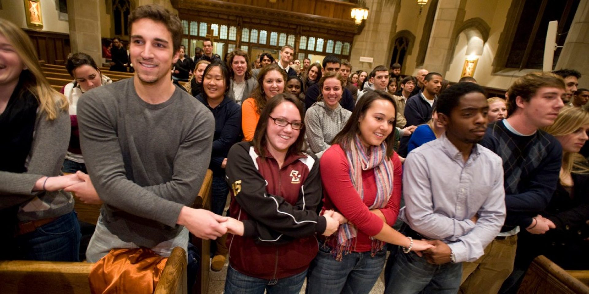 a crowd of people in a church holding hands with each other