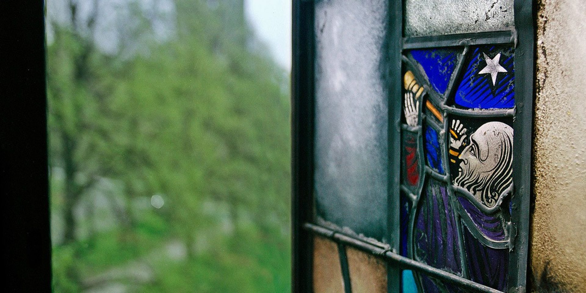 a stained glass window depicting a man looking at the stars with a telescope 