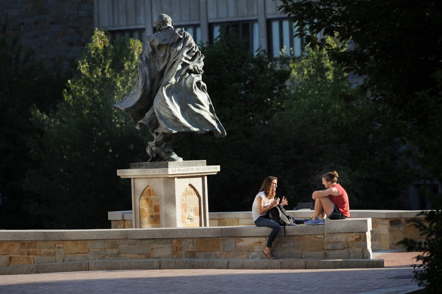 Two students sitting near the Saint Ignatius statue 