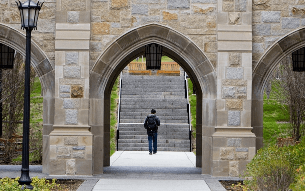 A student walking through an archway towards stairs