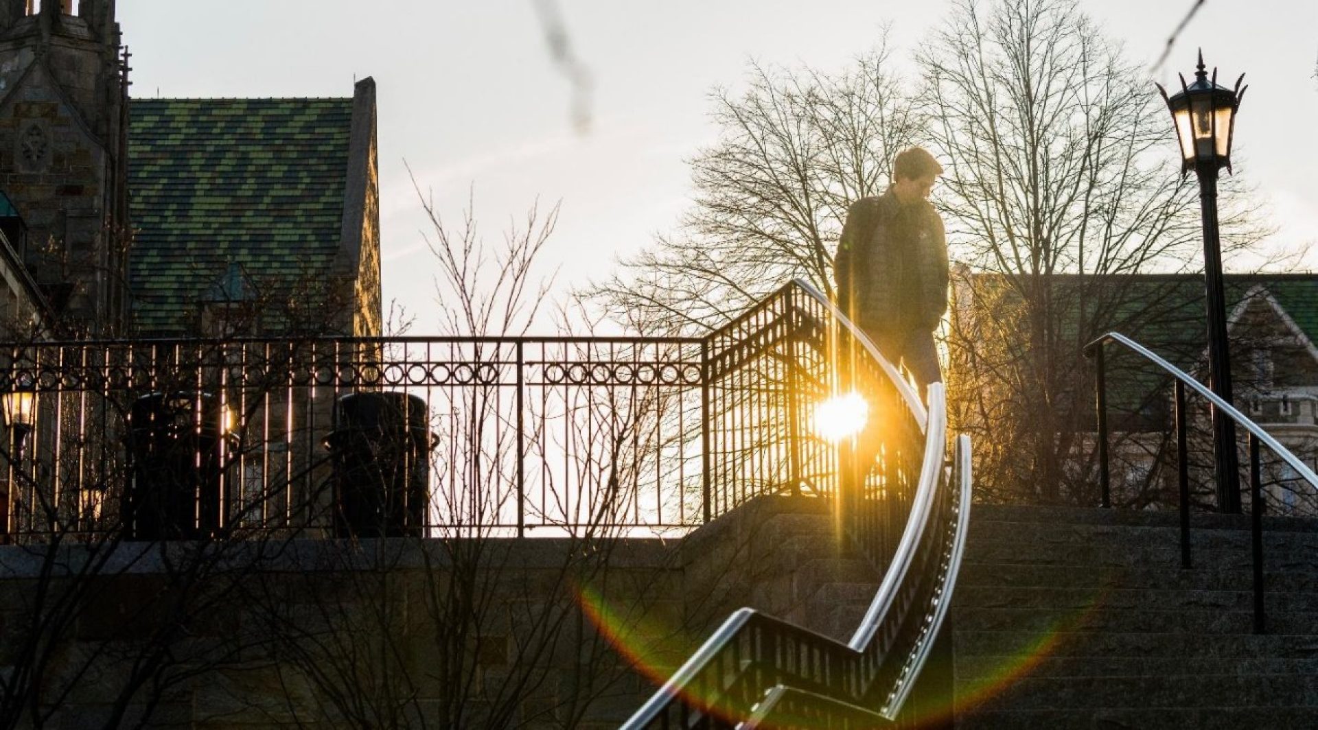 A student, walking down stairs outside at dawn.