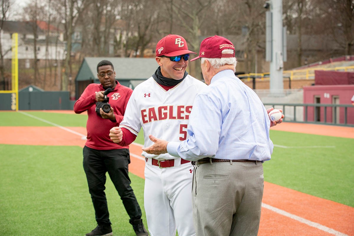 John Harrington speaks with player on baseball field.