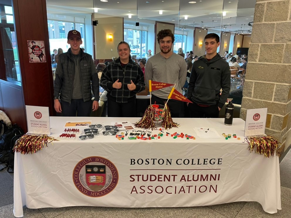 Student Alumni Association members stand at a information table