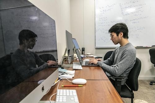 student sitting at desk looking at laptop