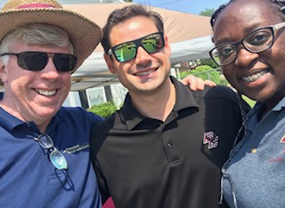 three people hugging at a community assistance program event