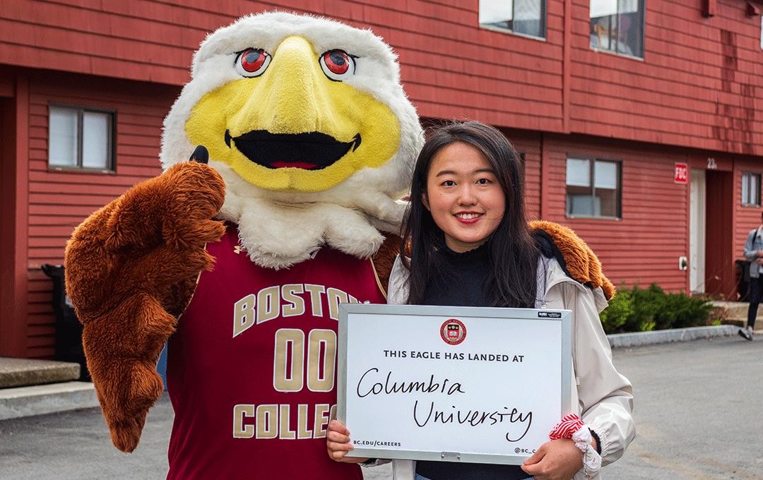 baldwin eagle mascot and student holding up a white board with columbia university written on it