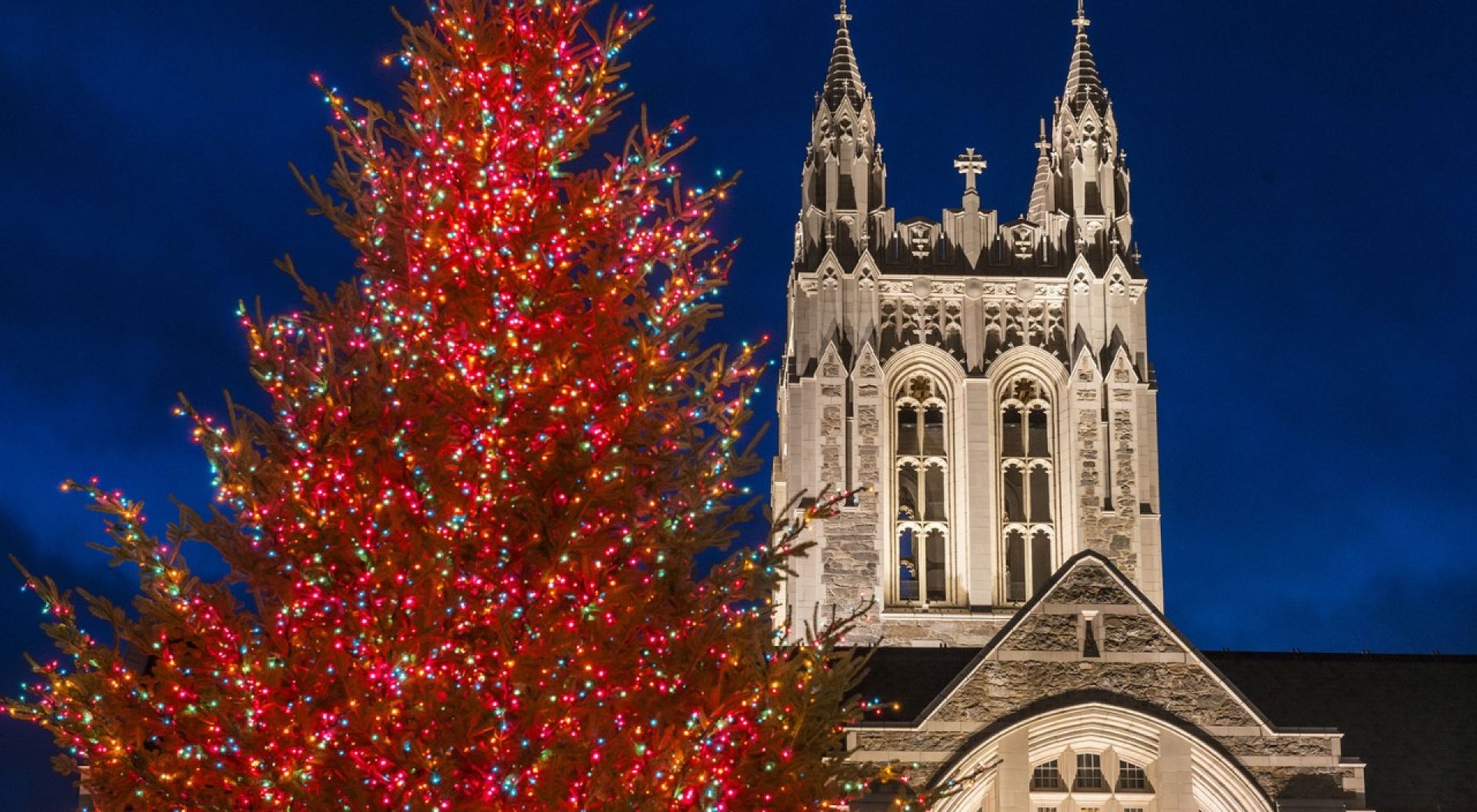 A lit Christmas tree in front of Gasson Hall