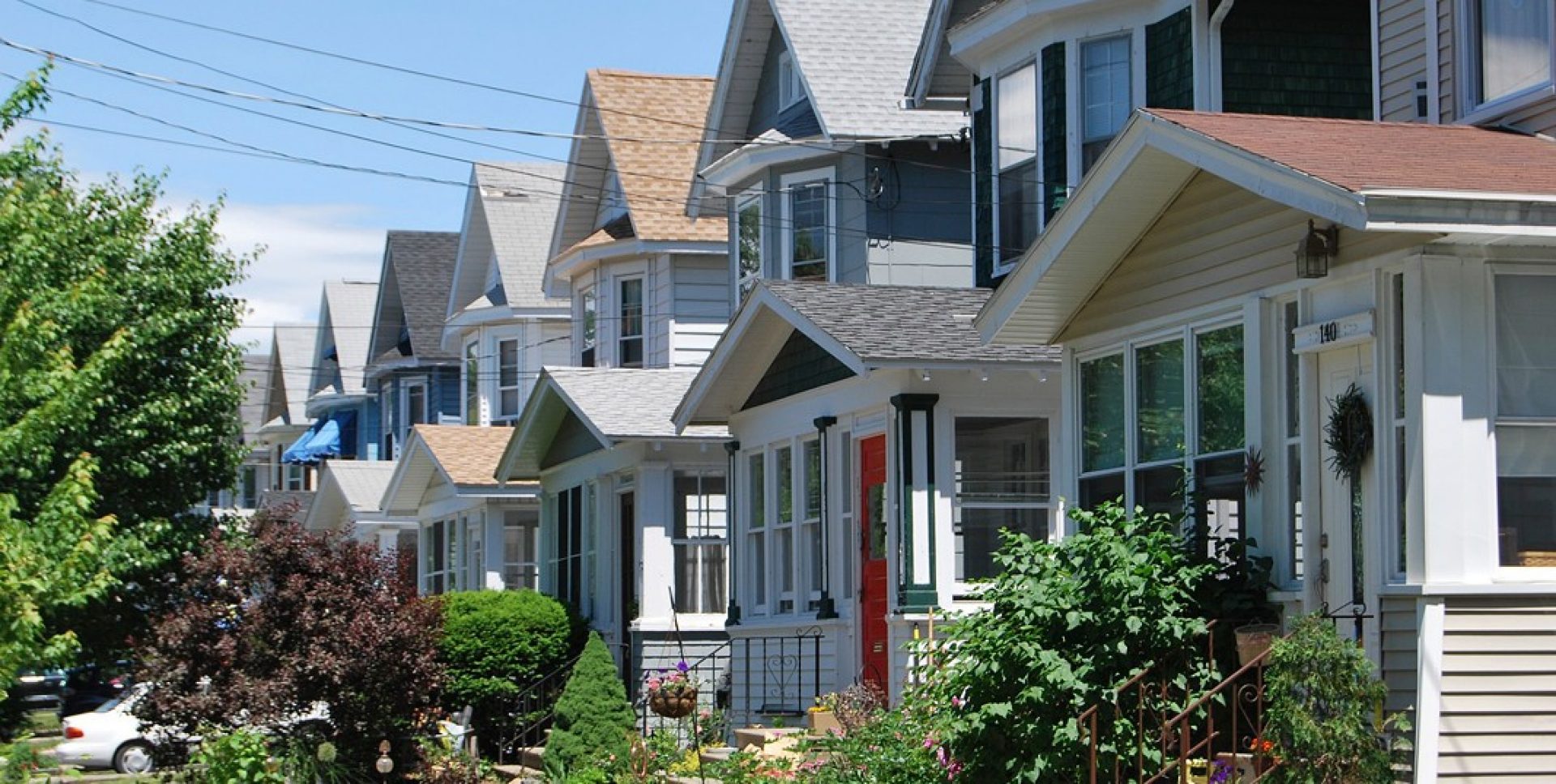 a row of houses with bushes and trees in the front yards