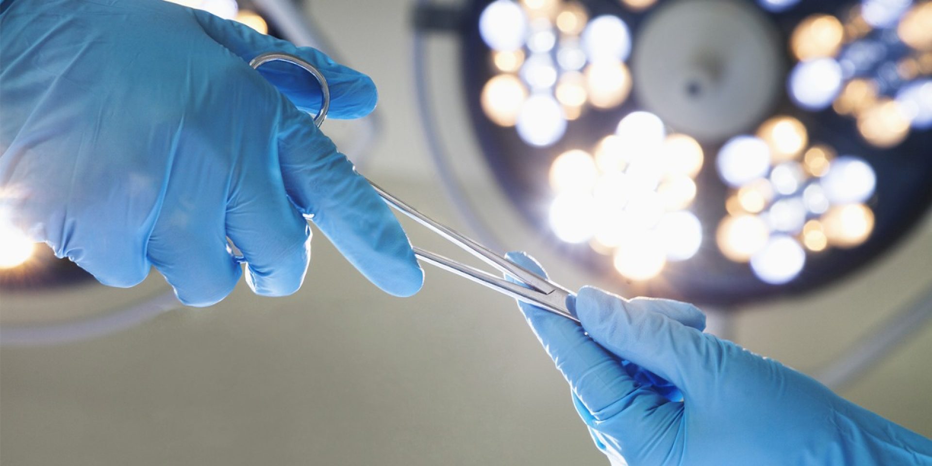 hands in gloves holding surgical tools