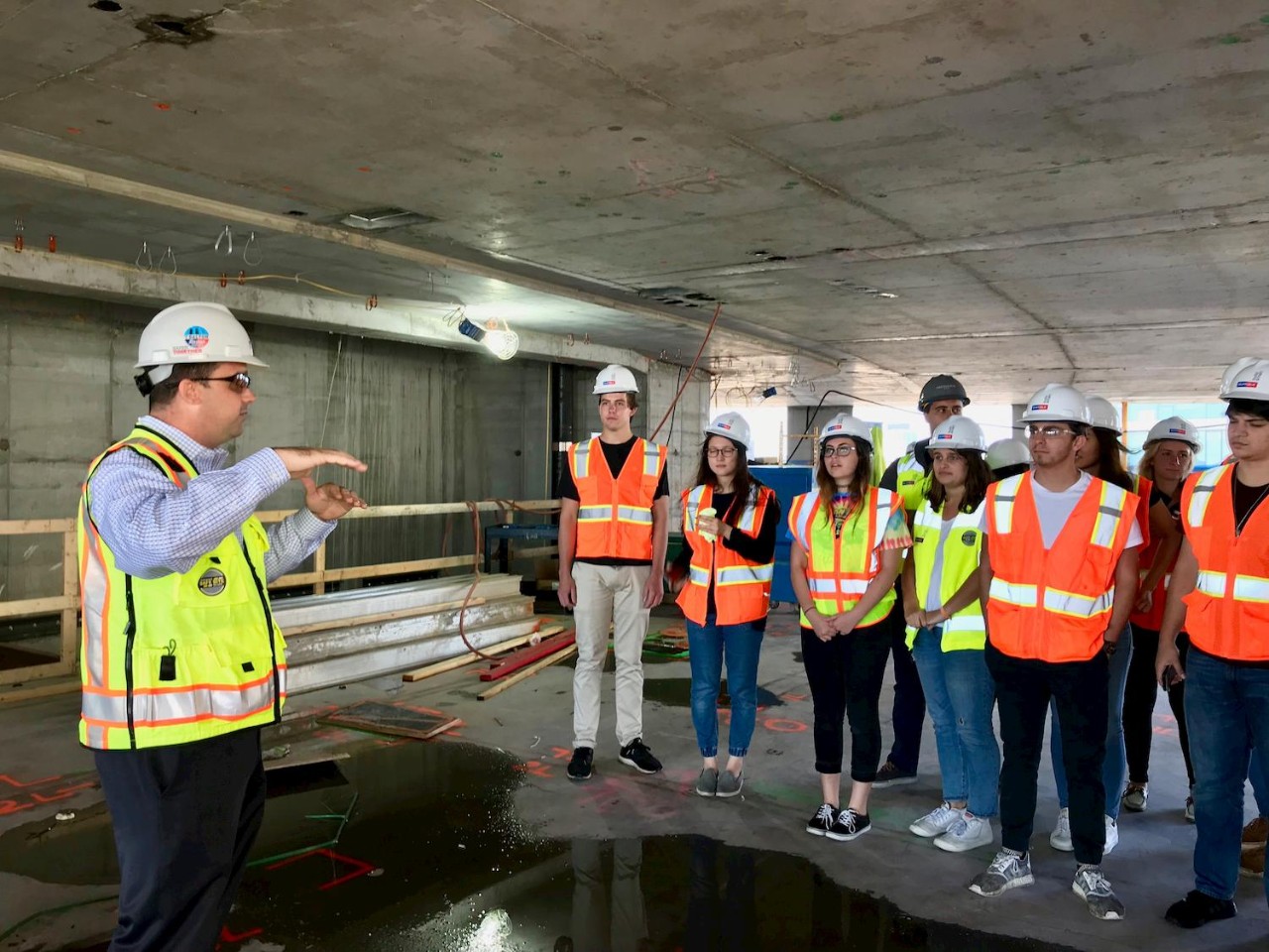 Students in hard hats and reflective vests on a class field trip for their Real Estate and Urban Action class