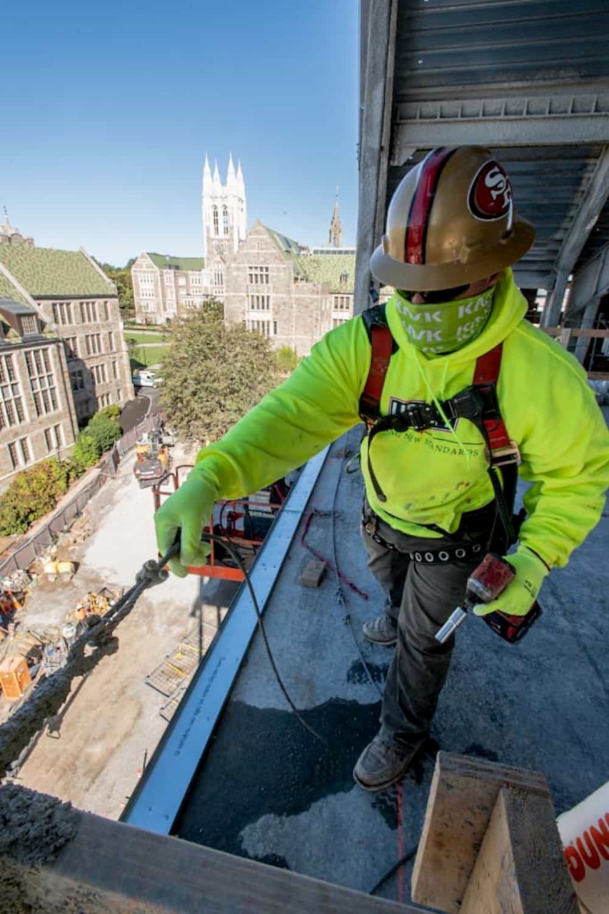 an aerial view of campus from the top of the new science building with a construction worker in the foreground